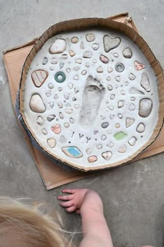 a child's hand and foot print on a paper plate with rocks in it