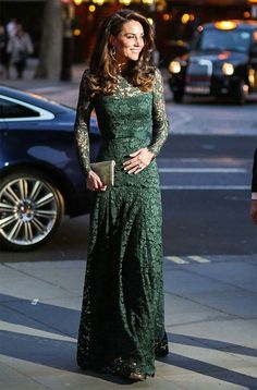 a woman in a green dress is standing on the sidewalk