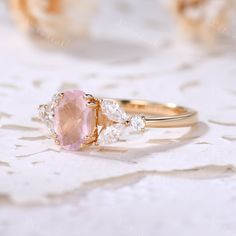 a pink and white ring sitting on top of a lace covered table with flowers in the background