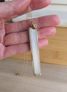 Selenite Necklace, Healing Stone, White Crystal Pendant, Gold Plated Selenite Pendant, Raw Natural Stone, Electroplated Gemstone, Long Bar **ABOUT THIS NECKLACE** **SEE MEASUREMENTS BELOW** This beautiful angelic stone pendant features a raw slice of selenite. This natural white bar is capped and rimmed around the edges in gold leaf. This pendant is two sided and features an organic, cloudy vertical pattern. Selenite comes from the Greek word Selene, which means moon. It is also known as a sweet Minimalist White Quartz Crystal Necklace, White Quartz Pendant Crystal Necklaces, Spiritual White Quartz Necklaces, White Quartz Pendant Necklace, Spiritual White Quartz Necklace, White Quartz Minimalist Necklace, White Quartz Necklace For Gift, Minimalist White Quartz Necklace, White Crystal Necklace With Natural Stones As A Gift