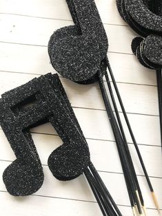 some black glittered objects are laying on a table with sticks and pencils next to them