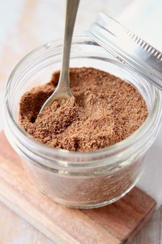 a spoon in a jar filled with brown powder on top of a wooden cutting board