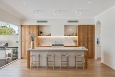 an open kitchen with wooden cabinets and white counter tops, along with bar stools