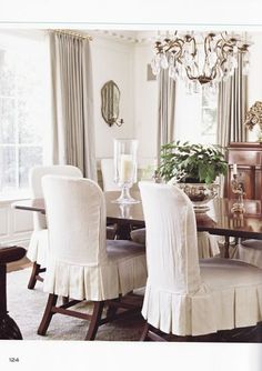 a dining room table with white chairs and a chandelier