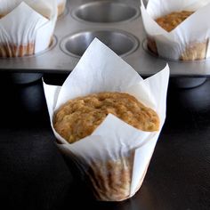 muffins sitting in paper wrappers on top of a metal baking pan, ready to be baked