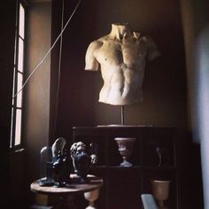 an image of a man's torso on display in a room with vases