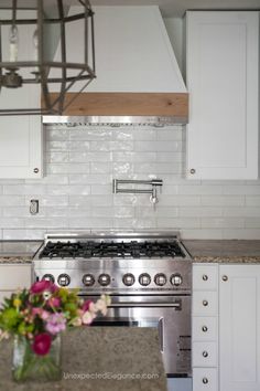 a kitchen with white cabinets and stainless steel stove top oven in the middle of it