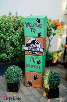 there is a cardboard welcome sign in front of some potted plants on the sidewalk