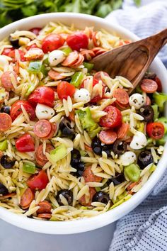 a white bowl filled with pasta salad and a wooden spoon