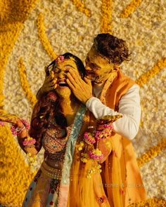 two people dressed in yellow and orange are hugging each other