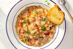 a white bowl filled with soup next to a piece of bread on top of a table