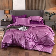 a bed with purple sheets and pillows in a room