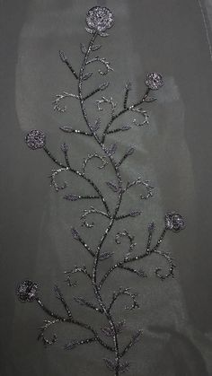 an embroidered piece of cloth with silver thread and flowers on it's back side