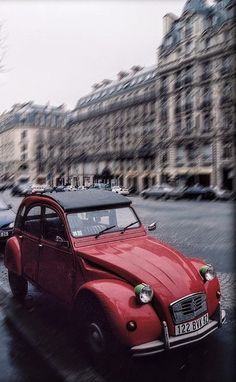 an old red car is driving down the street