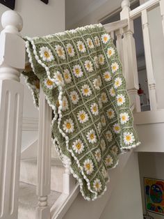 a green and white crocheted blanket sitting on top of a stair case next to a banister