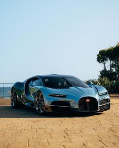 a blue bugatti is parked on the side of the road near water and trees