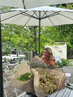 a woman sitting on a bench with flowers in her hands and an umbrella over her head