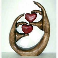 a sculpture with two hands holding red hearts