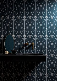 a bathroom with black and white wallpaper, gold faucet, mirror and sink