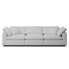 a white couch with four pillows on it's back and one arm facing the camera