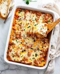 a casserole dish with meat, cheese and bread in it on a marble surface