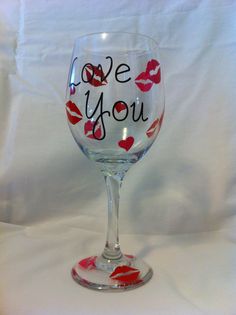 a wine glass with the words love you painted on it and lipstick kisses in red