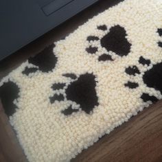 a rug with black and white cats on it next to a laptop computer, which is sitting on the floor