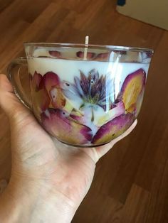 a person holding a glass cup with flowers on it