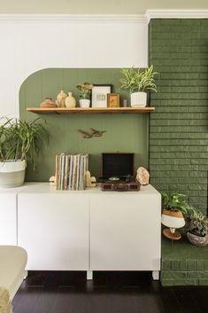 a living room filled with furniture and lots of plants on top of the shelfs