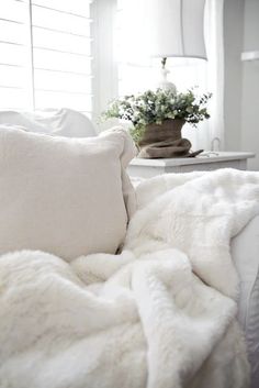 a bed covered in white blankets and pillows