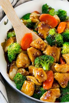 chicken and broccoli stir fry in a pan with a wooden spoon