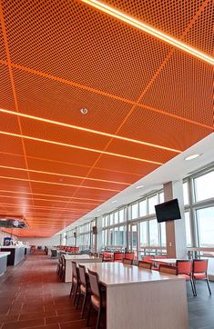 an empty room with tables and chairs in front of large windows that are lit by bright orange lighting