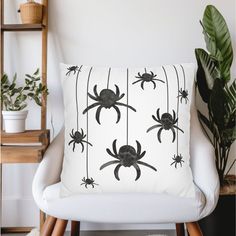 a black and white spider pillow sitting on top of a chair next to a potted plant