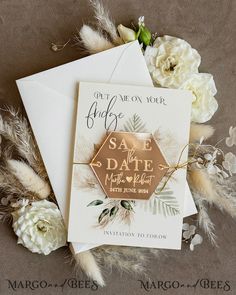 wedding save the date cards with white flowers and gold foil on them, sitting next to each other