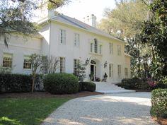 a large white house surrounded by trees and bushes