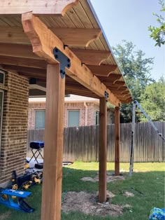 an outdoor covered patio with wooden posts and wood slats on the side of it