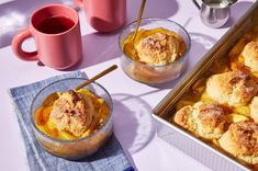 two bowls filled with dessert sitting on top of a table next to pink mugs