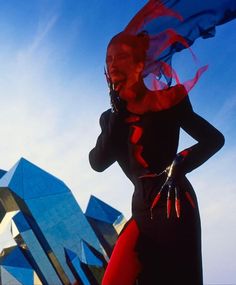 a woman is standing in front of a building with a red and blue scarf around her neck