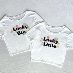 two white shirts with the words lucky little and lucky big printed on them, sitting next to each other