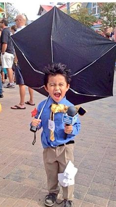 a young boy is holding an umbrella in the middle of his head and it looks like he's having fun