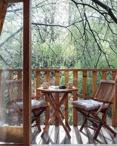 two wooden chairs sitting on top of a wooden deck next to a table and chair