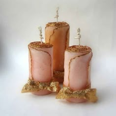 three pink candles with gold glitter bows on them