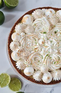 a pie with white frosting on top and limes around the edges next to it