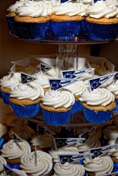 three tiered trays filled with blue and white cupcakes