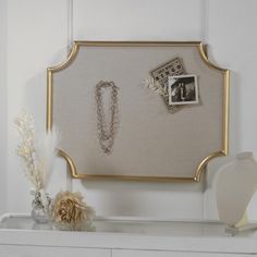 a white dresser with a gold frame and jewelry on it