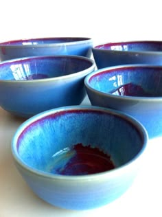 four blue bowls sitting on top of a white counter next to an orange and red object