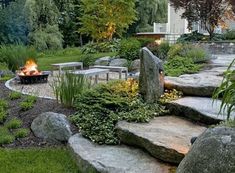 an outdoor fire pit surrounded by rocks and grass