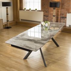 a marble table in an empty room with wooden floors and brick wall behind the table