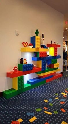 a room filled with lots of colorful legos on the wall and floor next to a blue carpet