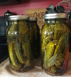 two jars filled with pickles sitting on top of a table